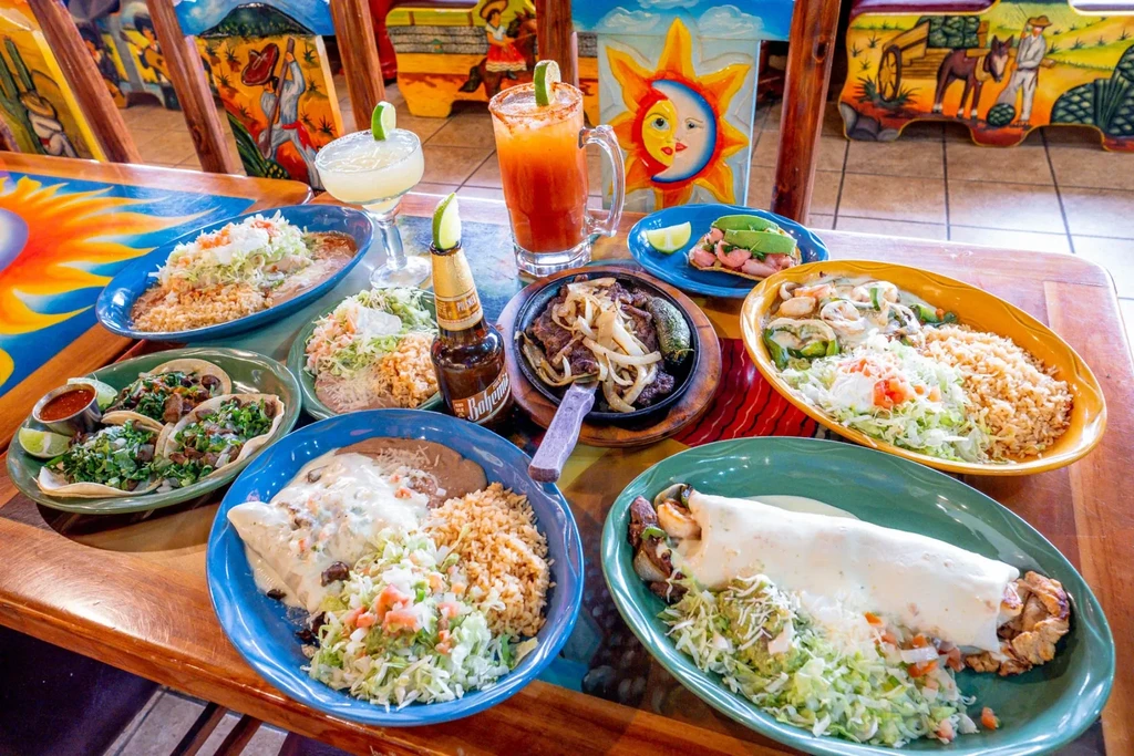 Extensive, colorful spread of Mexican food and drinks on a wooden table.