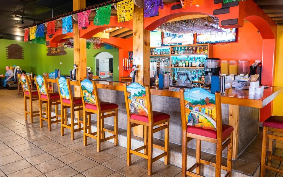 Colorful Mexican restaurant bar with hand-painted stools and papel picado.