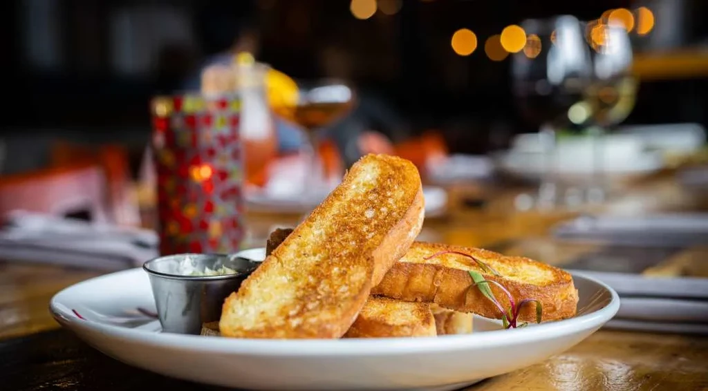 Crispy golden-brown toasted bread with dipping sauce on a white plate.