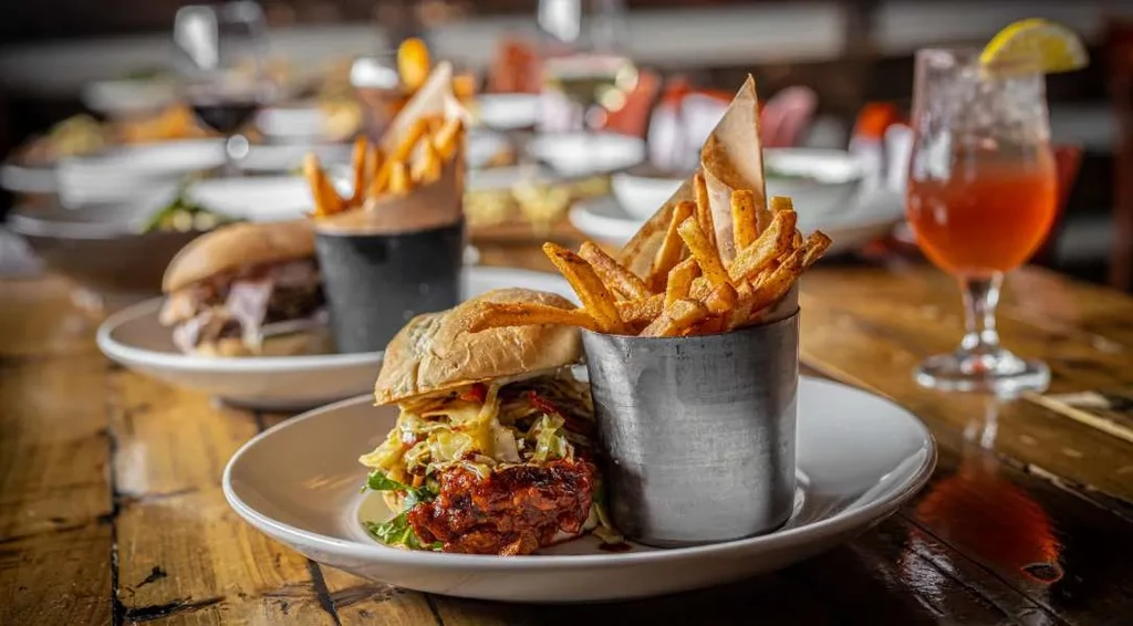 Gourmet burger with fries and drinks on a wooden table.