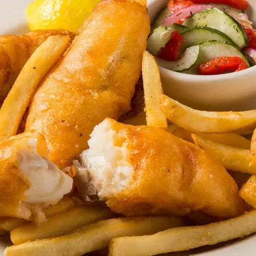 Close-up: Golden fish and chips, side salad, and lemon wedge.