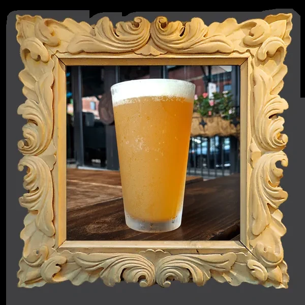 Frosted glass of frothy amber beer on wood, in an ornate frame.
