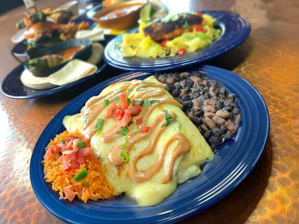 Blue plate with cheese-covered dish, Spanish rice, and mixed beans.