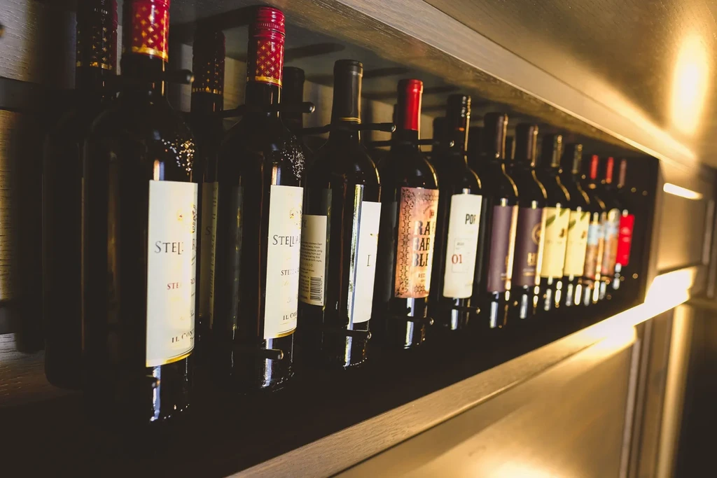 Stella red wine bottles displayed horizontally on a dark wood shelf.