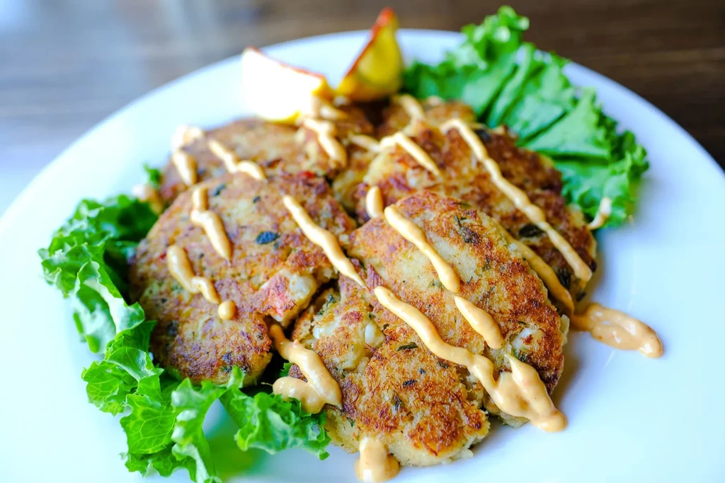 Five golden pan-fried patties with sauce, lettuce, and citrus.