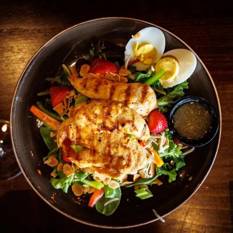 Top-down grilled chicken salad with strawberries, egg, and almonds.