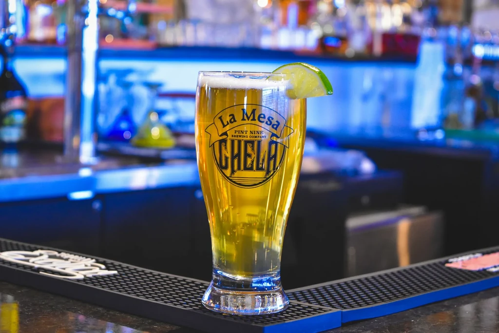 La Mesa Pint Nine CHELA beer, foam, and lime on bar mat.