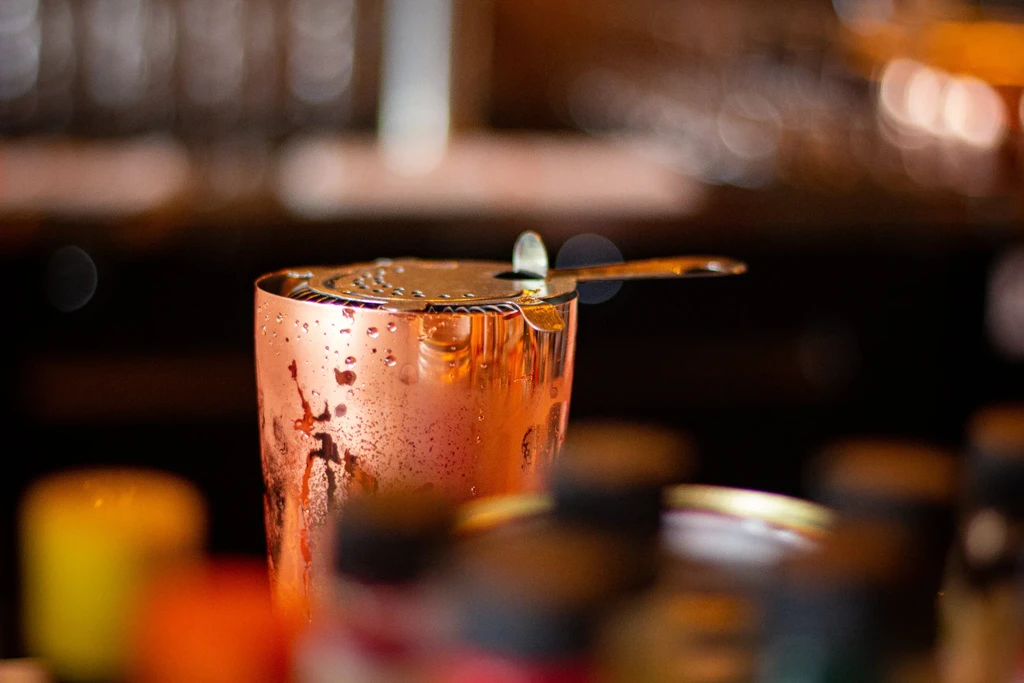 Wet copper cocktail shaker with a metal Hawthorne strainer.