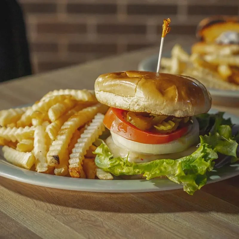 Hamburger with lettuce, tomato, pickles, and crinkle-cut fries.
