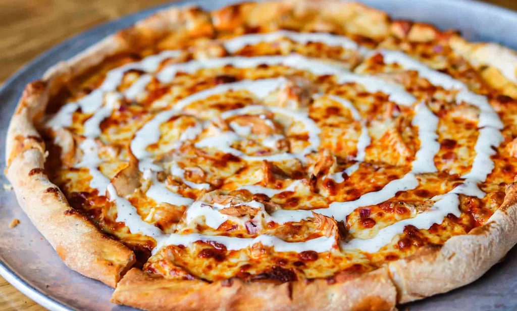 Baked pizza with chicken, melted cheese, and creamy spiral sauce.