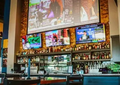Modern sports bar with large screen, three TVs, and full bar.