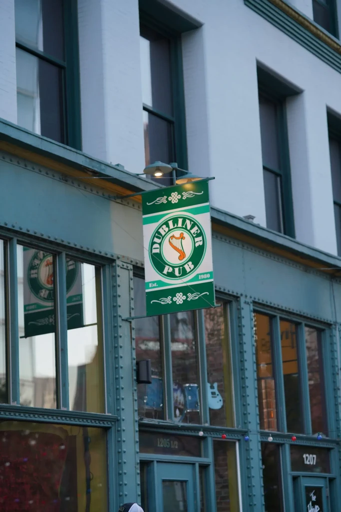 Green and white 'DUBLINER PUB Est. 1980' sign on building.