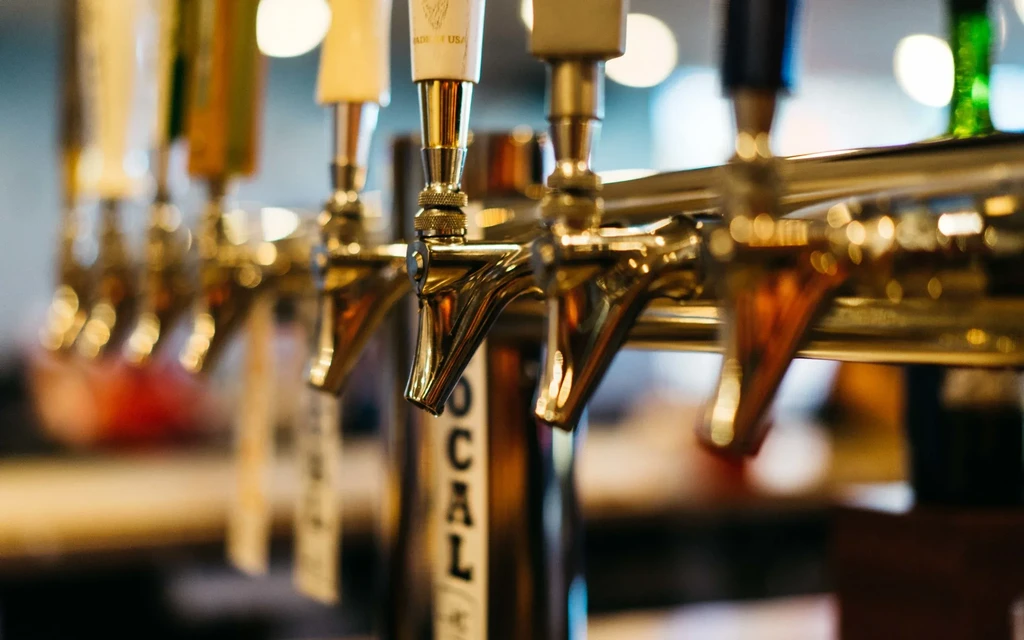 Close-up of polished metallic beer taps in a bar, one labeled 'LOCAL'.