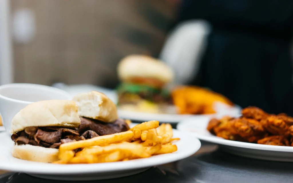 Plates of roast beef sandwich, french fries, and chicken wings.