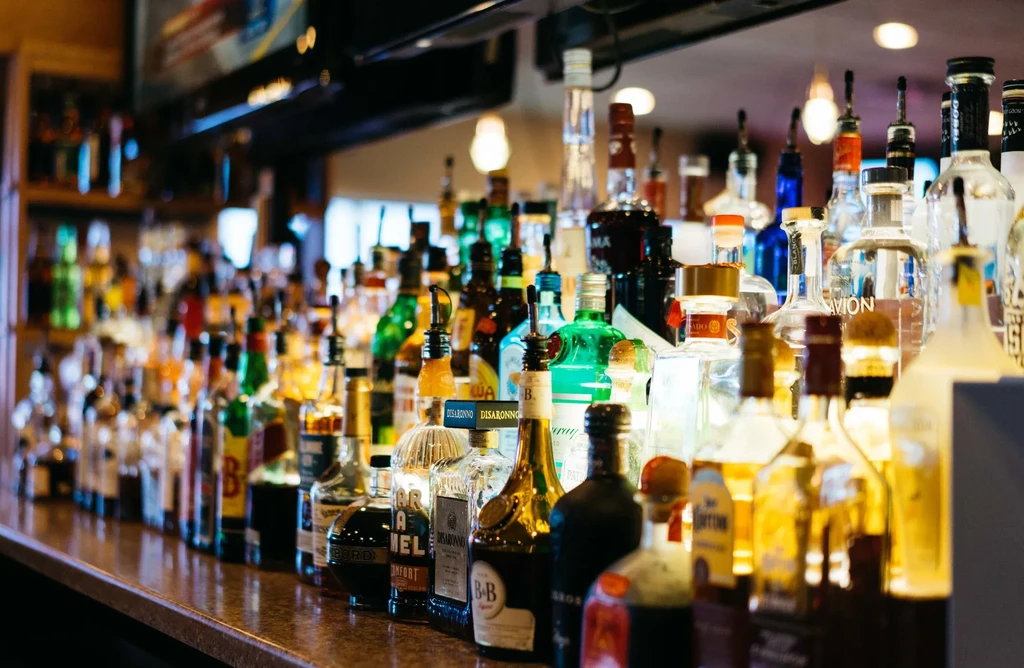 Well-stocked bar counter featuring many colorful liquor bottles and pour spouts.