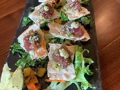 Diced tuna tartare on crispy crackers with mango and creamy sauce.