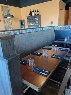 Empty dining room with dark table, booth seating, and wine display.