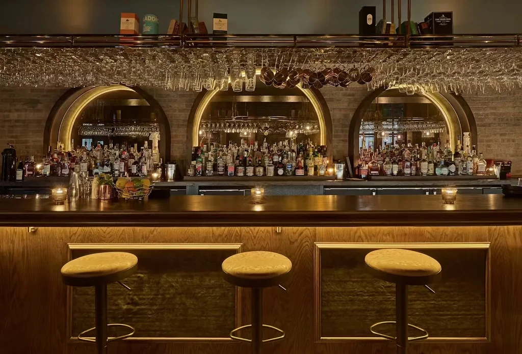 Dimly lit upscale bar with a wide array of liquor bottles.