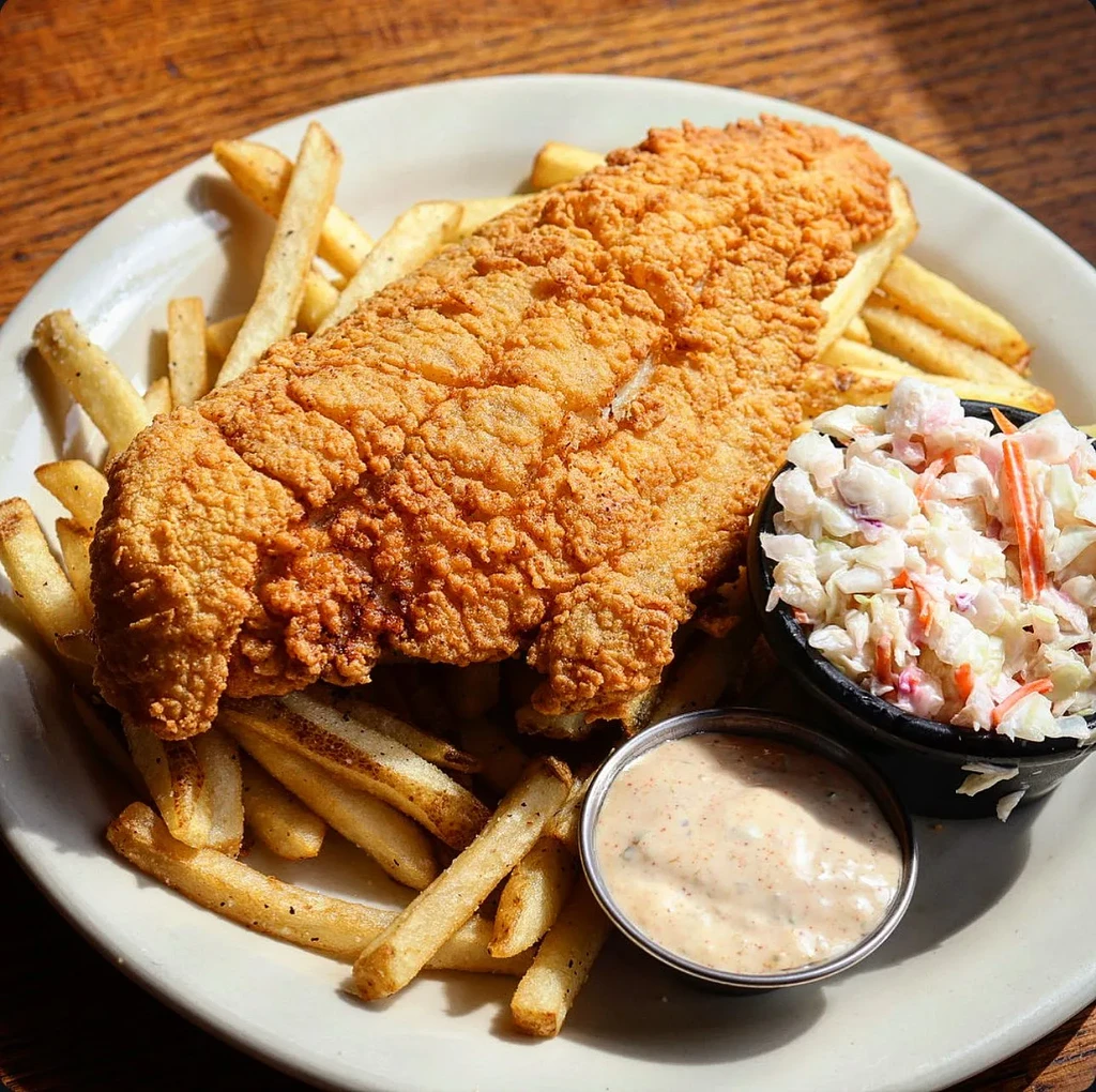 Fried fish or chicken with fries, coleslaw, and dipping sauce.