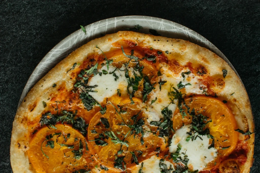 Freshly baked pizza with golden crust, tomatoes, melted cheese, and basil.