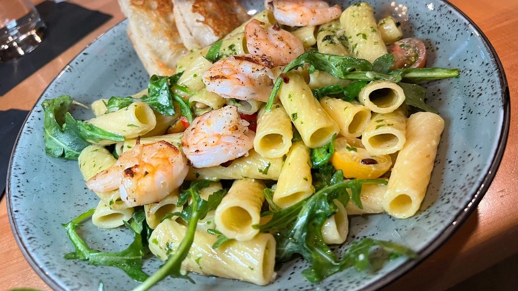 Grilled shrimp pasta with arugula and yellow tomatoes.