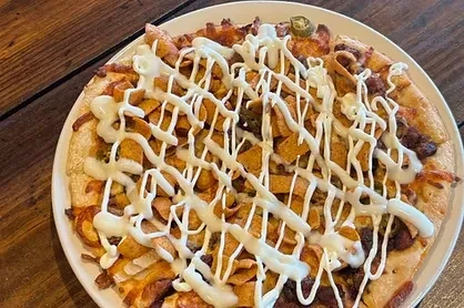 Overhead flatbread pizza with chips, meat, jalapeños, white sauce.