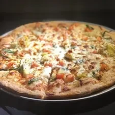 Whole pizza topped with melted cheese, tomatoes, artichoke hearts, herbs.