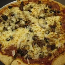 Partially sliced pizza topped with meat, mushrooms, olives, and bubbly mozzarella.