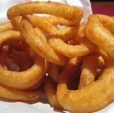Golden-brown, crispy, irregularly shaped onion rings on paper.