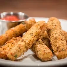 A plate of golden-brown fried cheese sticks with red dipping sauce.
