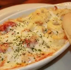 Cheesy baked pasta with red sauce, green herbs, and bread.