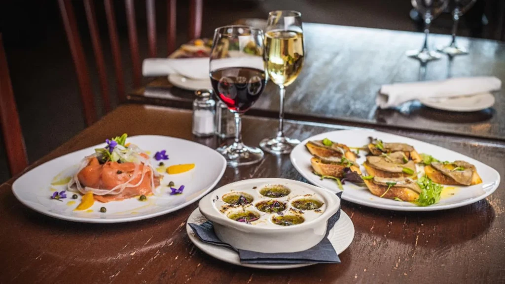 Restaurant table with salmon, escargots, pâté, red and white wines.