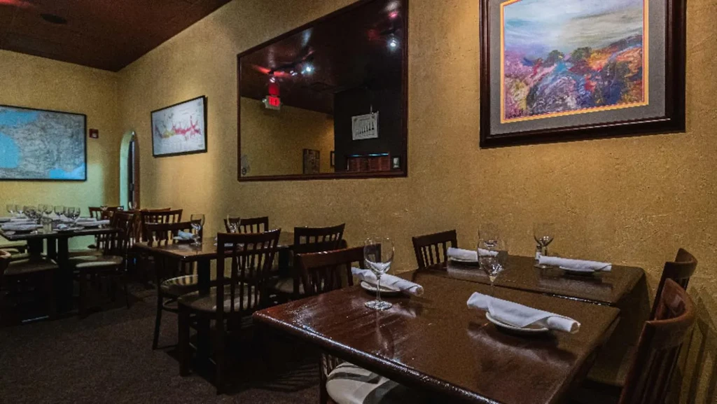 Restaurant interior: yellow walls, dark wooden tables, and various framed art.