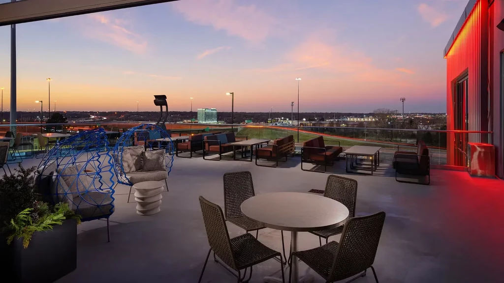 THOUGHT
The user wants alt-text for an image description.
The alt-text needs to be:
- Short (7-12 words)
- Factual
- No marketing language
- Concise and descriptive
- Return ONLY the alt text.

Image description breakdown:
- Modern rooftop terrace/bar at d