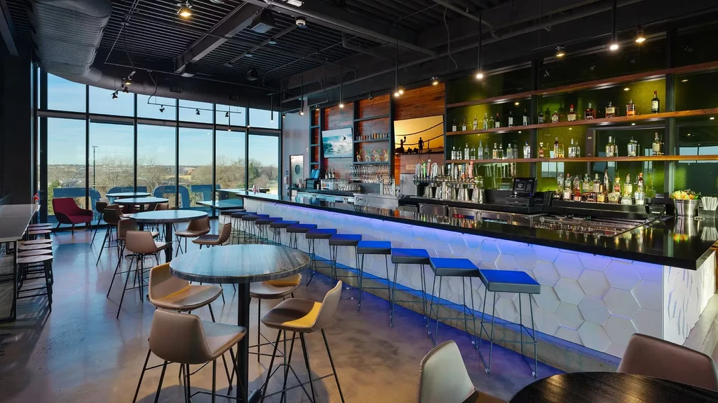 Modern restaurant bar with a well-stocked counter and floor-to-ceiling windows.