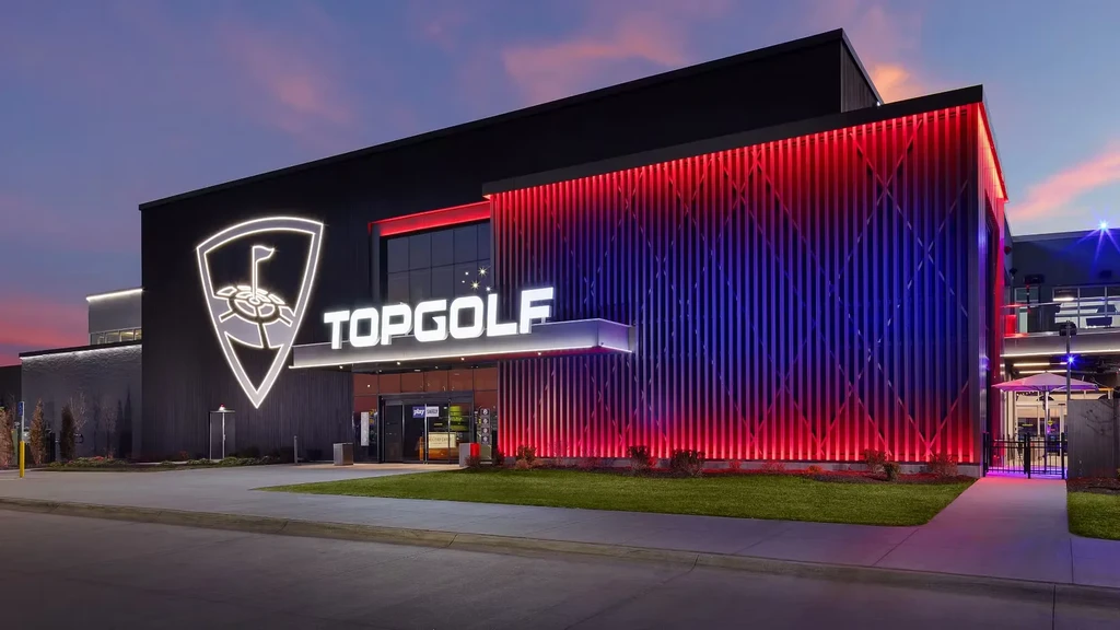 Topgolf building exterior at dusk, featuring red and blue lights.