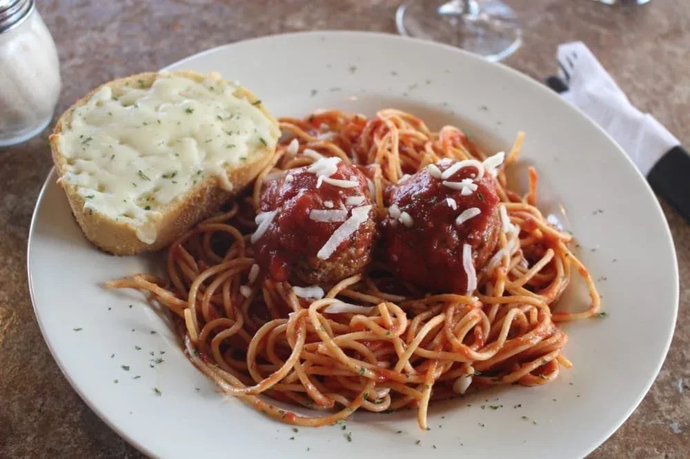 Close-up of spaghetti and meatballs with cheesy garlic bread.