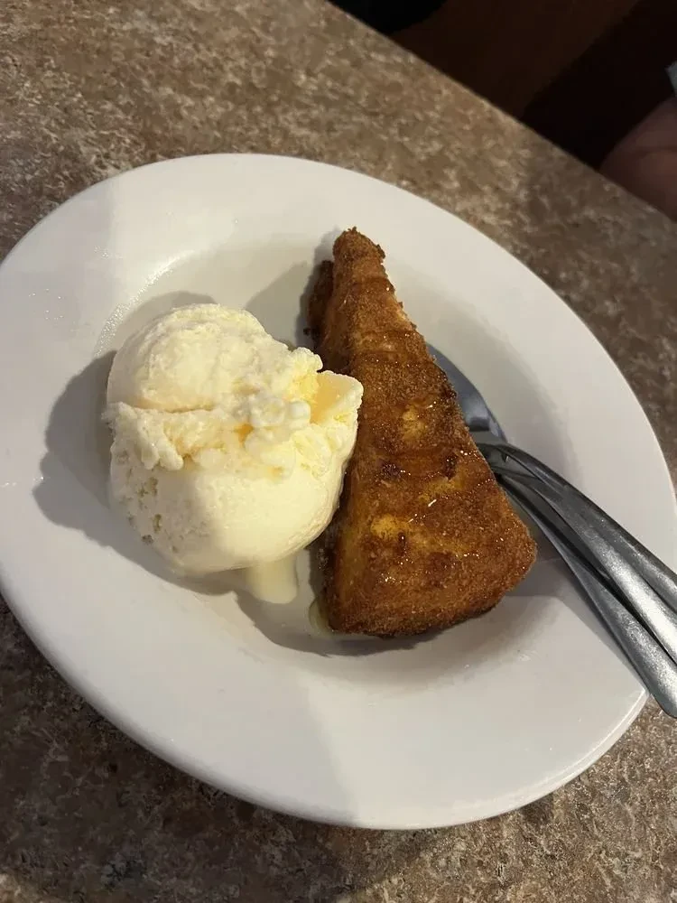 Vanilla ice cream, golden fried food with syrup on white plate.