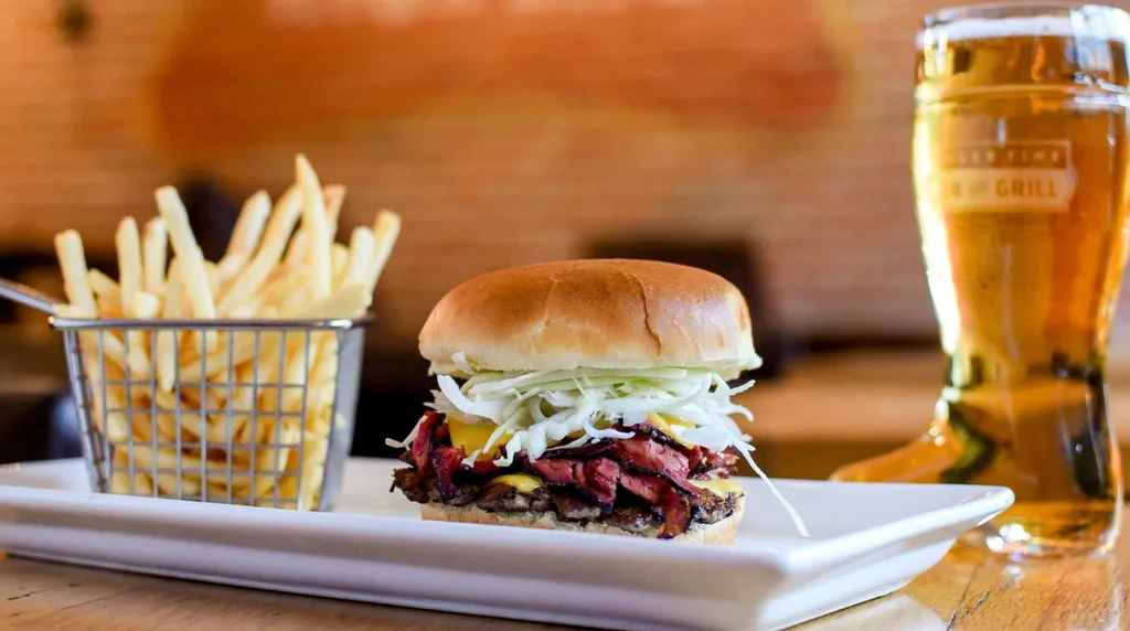A loaded burger, crispy fries, and a tall glass of beer.