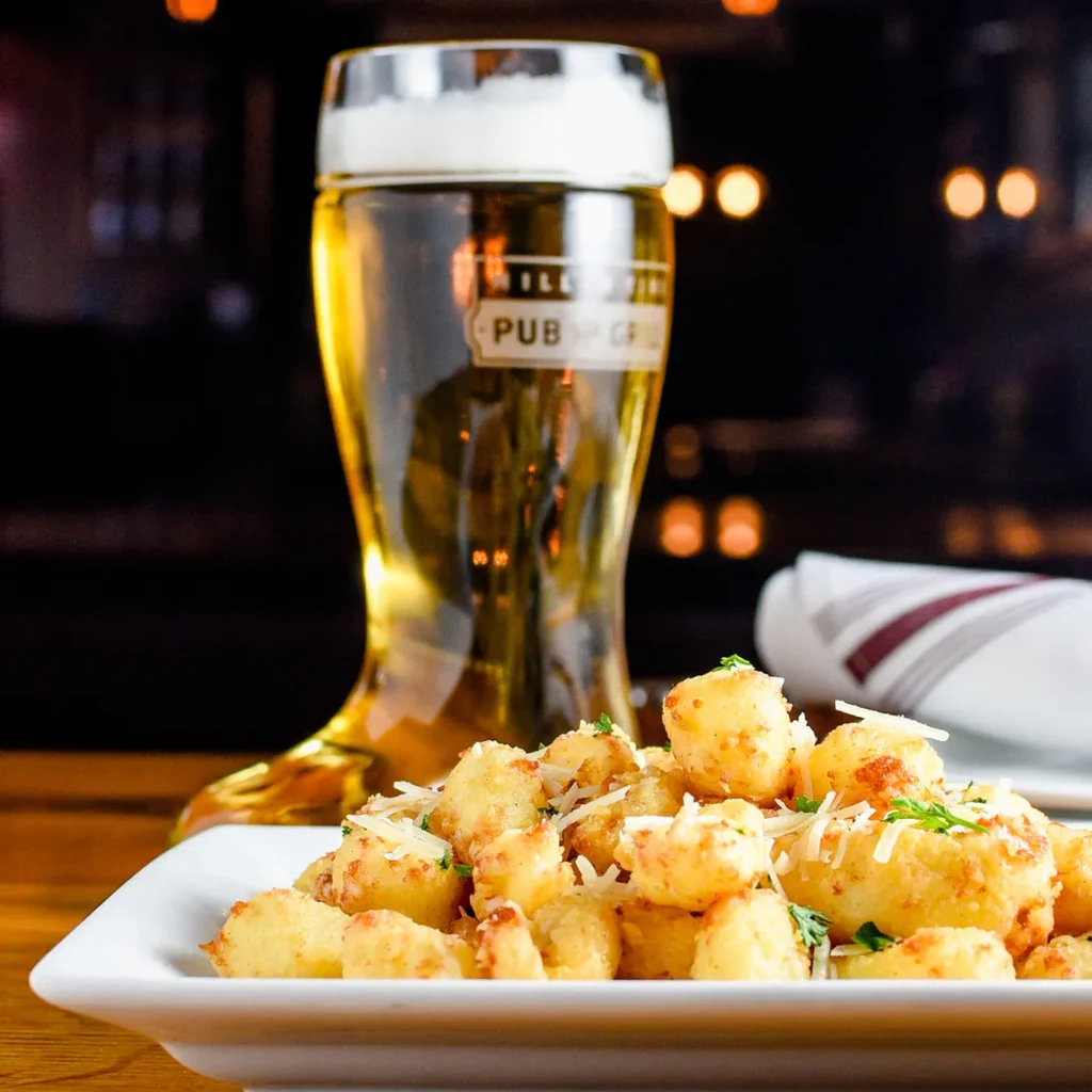 Golden-brown fried appetizers with cheese, herbs, and a boot-shaped beer glass.