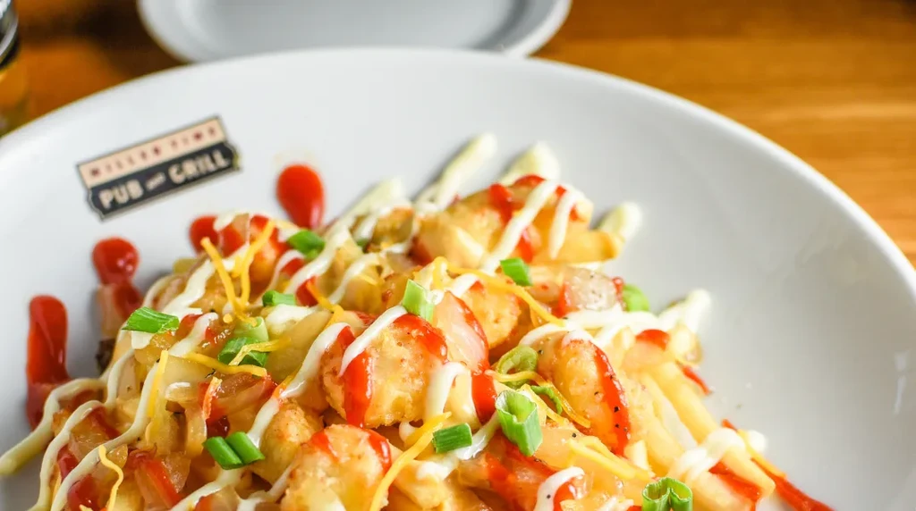 Loaded fries or tots with cheese, white sauce, ketchup, green onions.