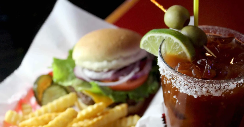 Close-up of a burger, crinkle fries, and a garnished Bloody Mary.
