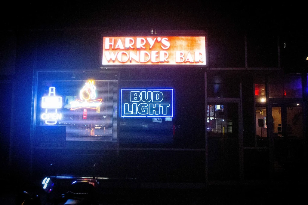Night view of Harry's Wonder Bar lit by red and blue neon.