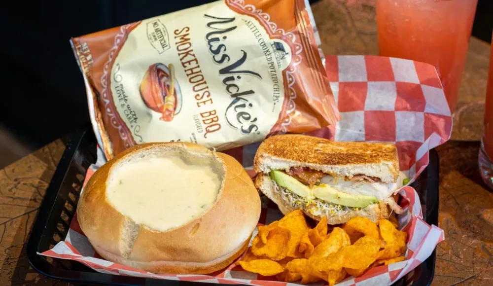 Creamy soup in bread bowl, grilled avocado sandwich, and Miss Vickie's chips.