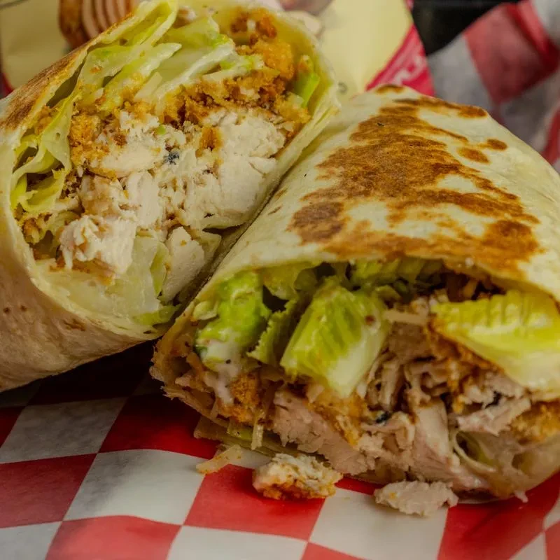 Grilled chicken wrap, sliced, showing lettuce, sauce, and breaded chicken.