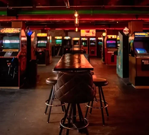 High-top table and stools in a vibrant vintage arcade bar.