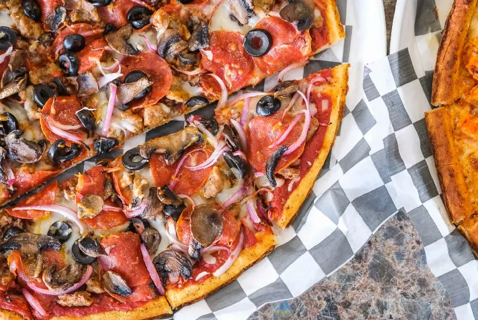 Sliced pizza with pepperoni, black olives, mushrooms, and ground sausage.