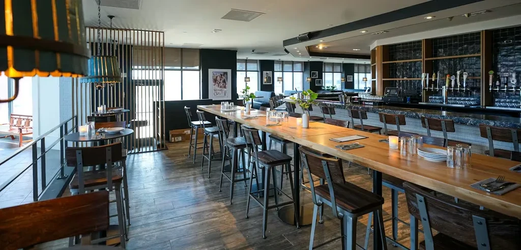 Empty contemporary restaurant with long communal table and bar.