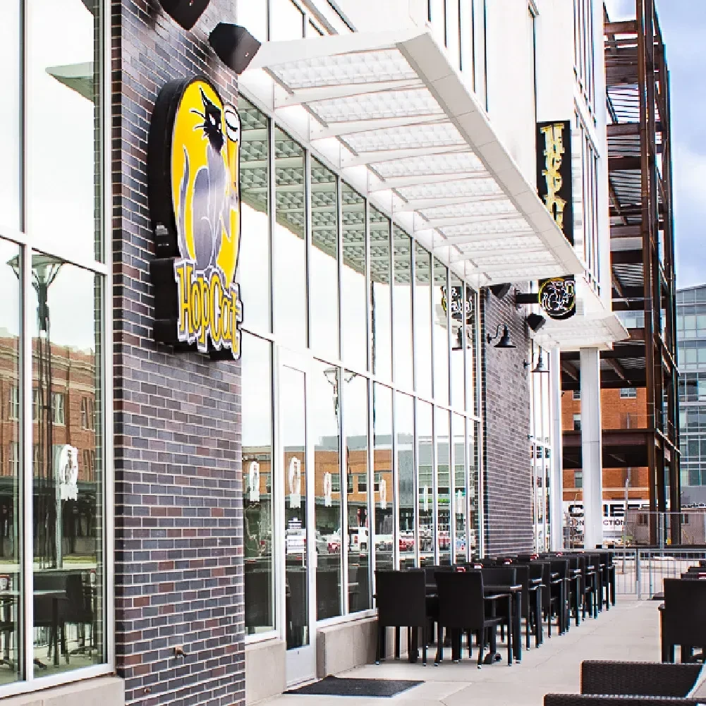 HopCat restaurant exterior: dark brick, glass, prominent sign, and patio.