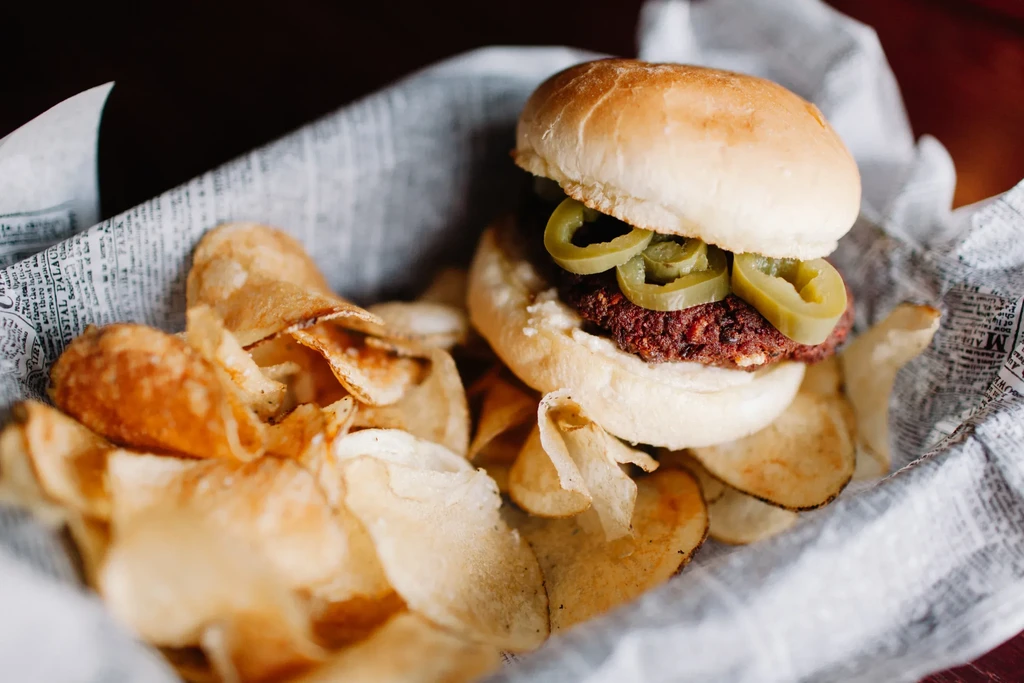 Close-up of a jalapeño burger and golden chips in a basket.